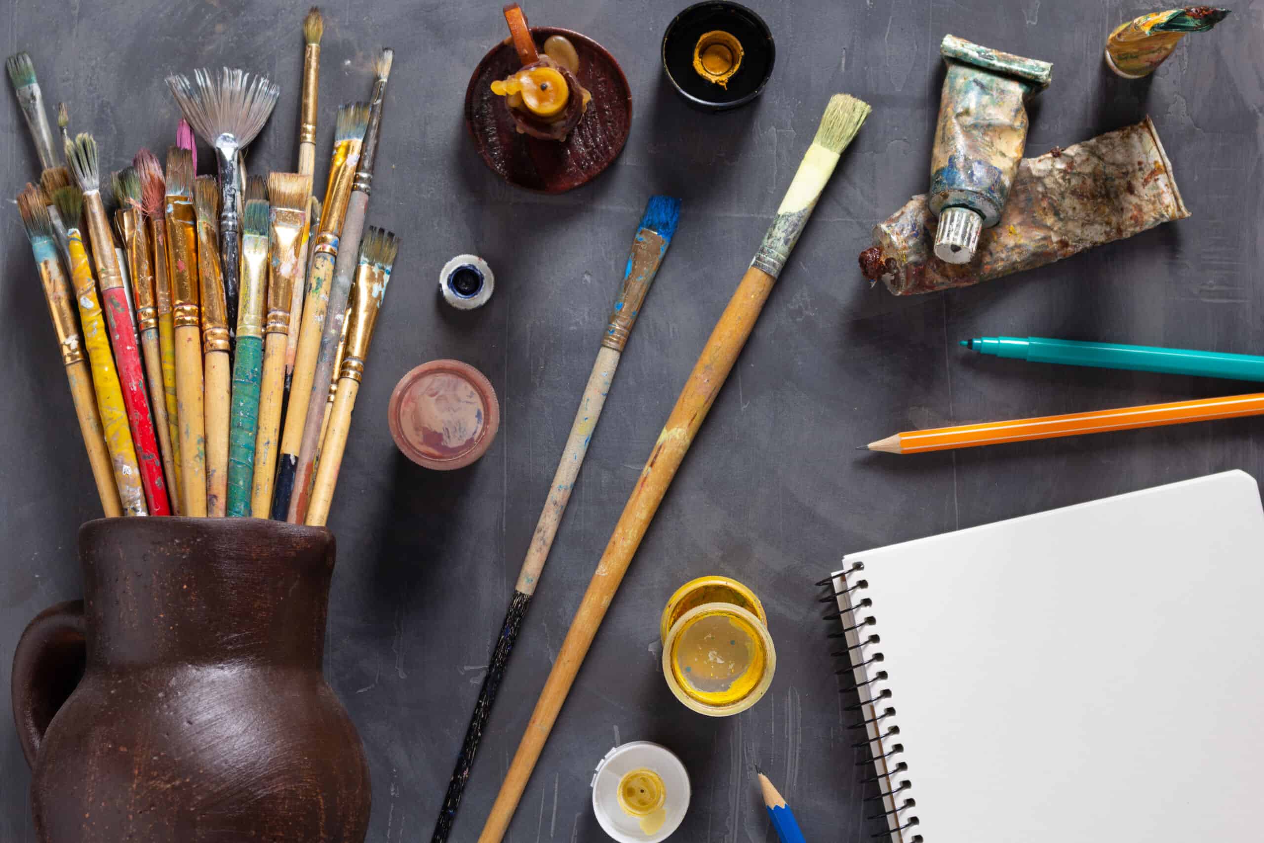 Paintbrush and tubes with painter tools at abstract table backgr